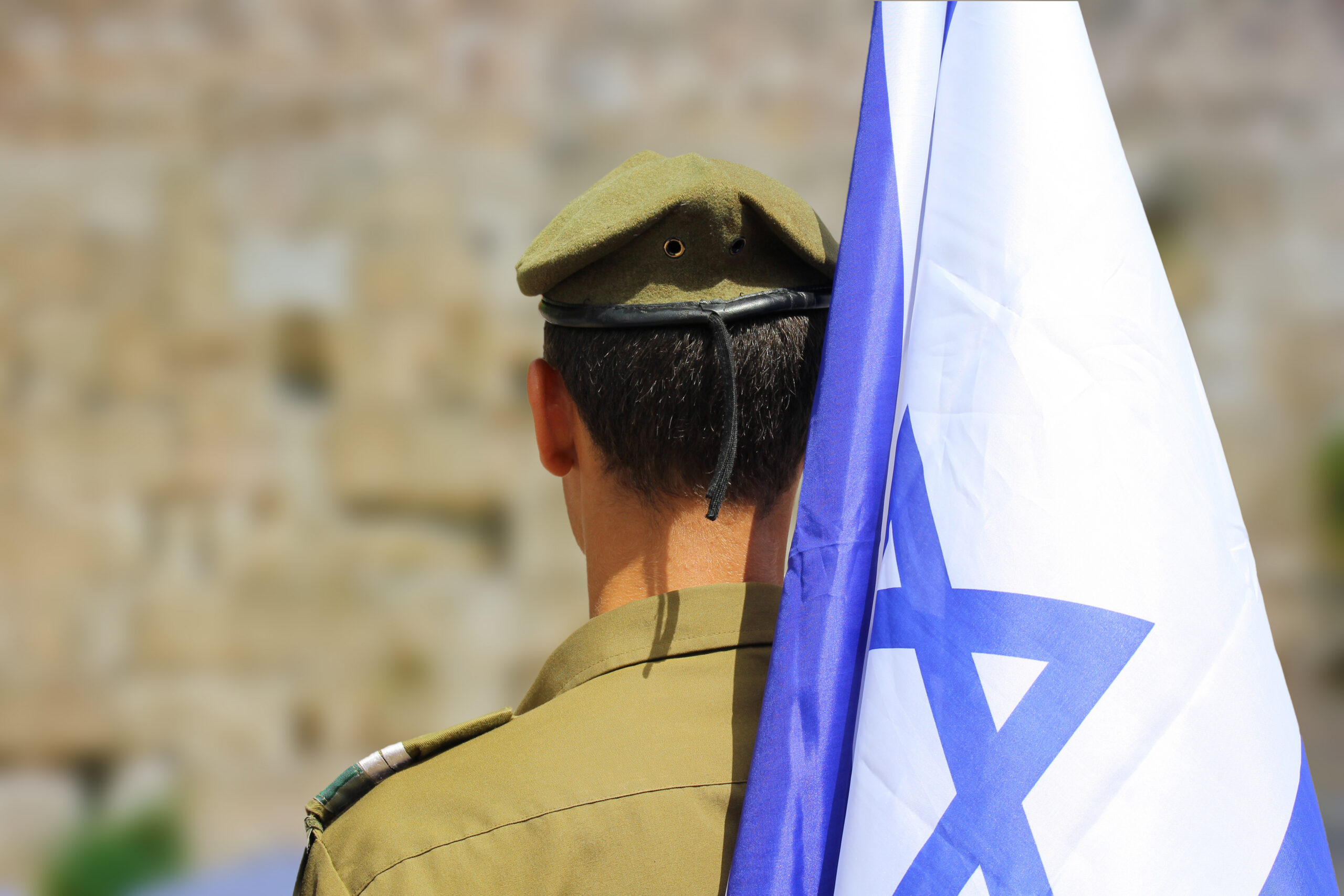 Israeli soldier with flag of Israel on blurred background of Western Wall